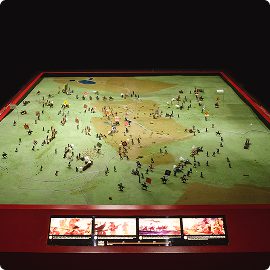 A diorama features miniature figures arranged on a terrain model, depicting the Battle of Aughrim with information panels and illustrations along the front edge.